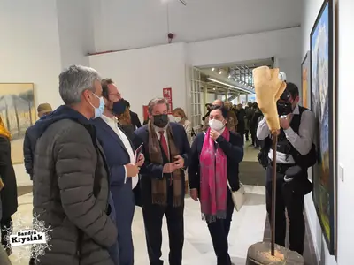 Grupo conversando junto a una escultura en una exposición
