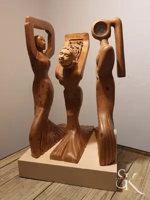 Tres figuras estilizadas talladas en madera sobre una base común