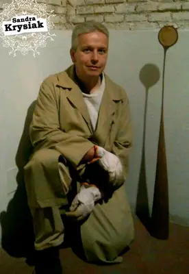 Retrato de un hombre junto a esculturas expuestas