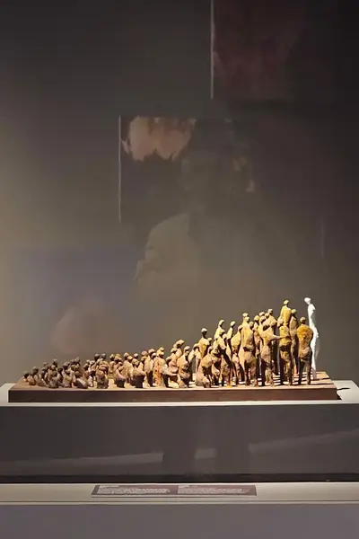 Pequeñas figuras de madera dispuestas sobre una base, en una vitrina de exposición