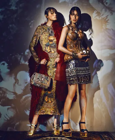 Dos modelos posan con abrigos de gala sobre corsés de madera tallada, en una editorial de moda fotografiada en penumbra