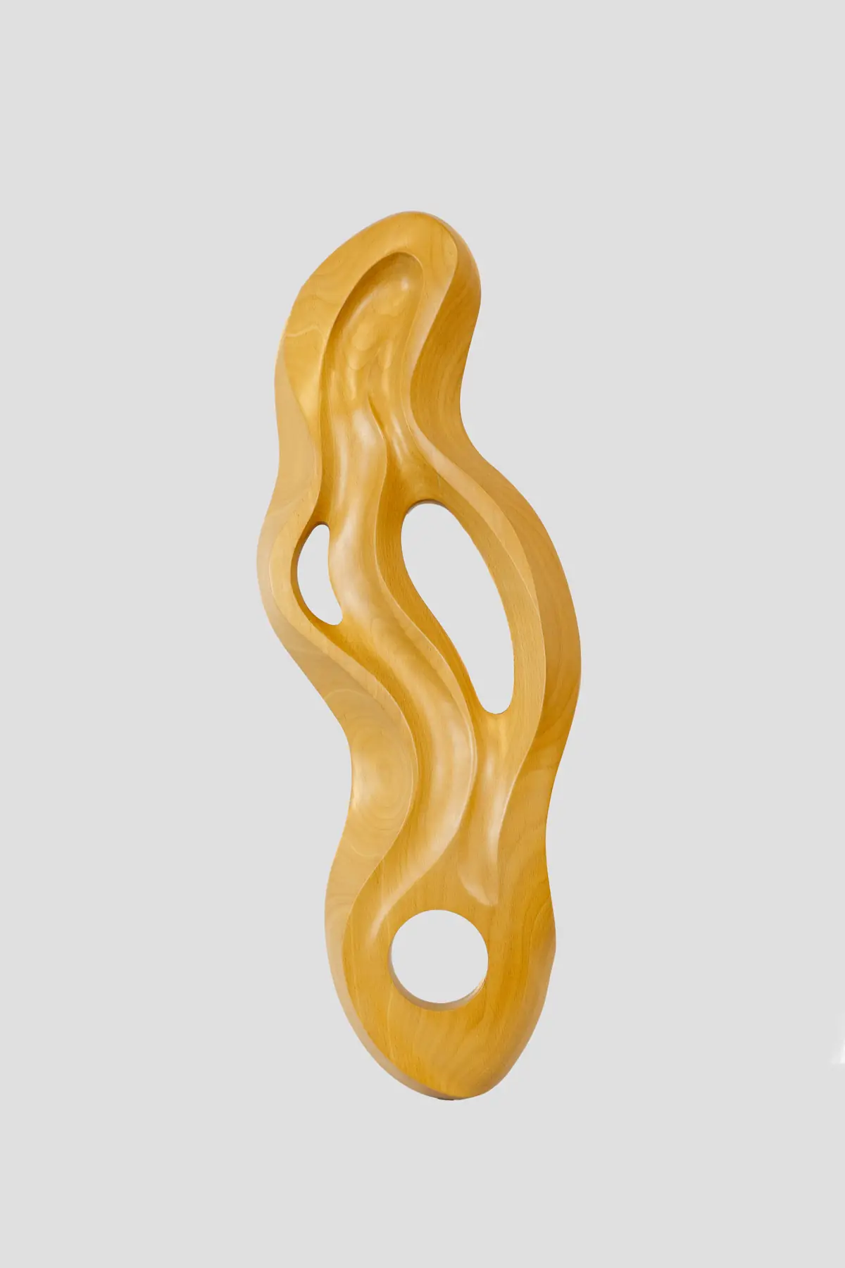 Escultura vertical de madera de haya, de forma sinuosa y alargada, atravesada por dos vacíos alargados