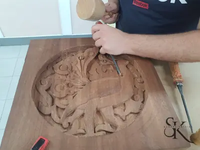Manos tallando un panel circular de hojas