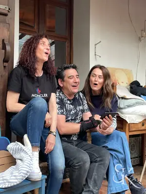 Tres personas sentadas cantando con una guitarra