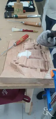 Manos trabajando una pieza entre virutas