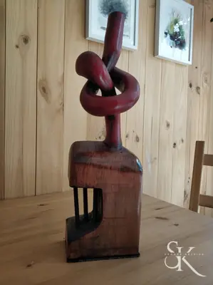 Escultura de madera con un lazo en la parte superior
