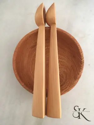 Dos figuras estilizadas ante un disco de madera