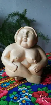 Figura sentada sobre una tela de colores