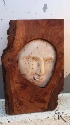 Rostro tallado en el centro de una tabla irregular