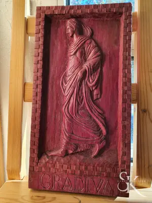 Figura de pie tallada en un panel rojizo