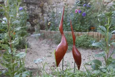 Dos aves estilizadas de madera en un jardín