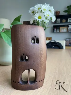 Recipiente cilíndrico con flores y pequeños huecos