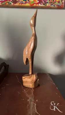 Figura alargada de madera sobre una peana