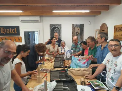 Grupo alrededor de la mesa del taller trabajando y mostrando sus piezas