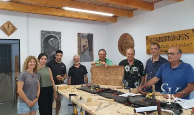 Grupo sonriente junto a una mesa con herramientas y un relieve terminado