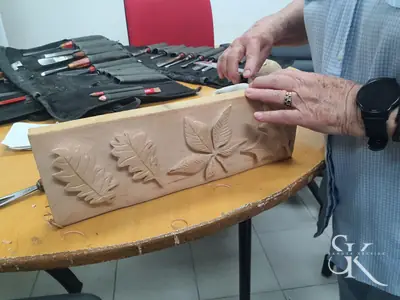 Alumno tallando un relieve de hojas junto a sus herramientas