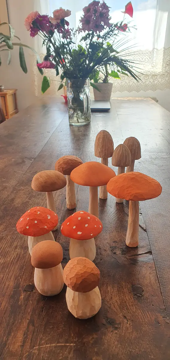 Setas talladas en madera y pintadas en tonos naranjas y marrones, colocadas sobre una mesa