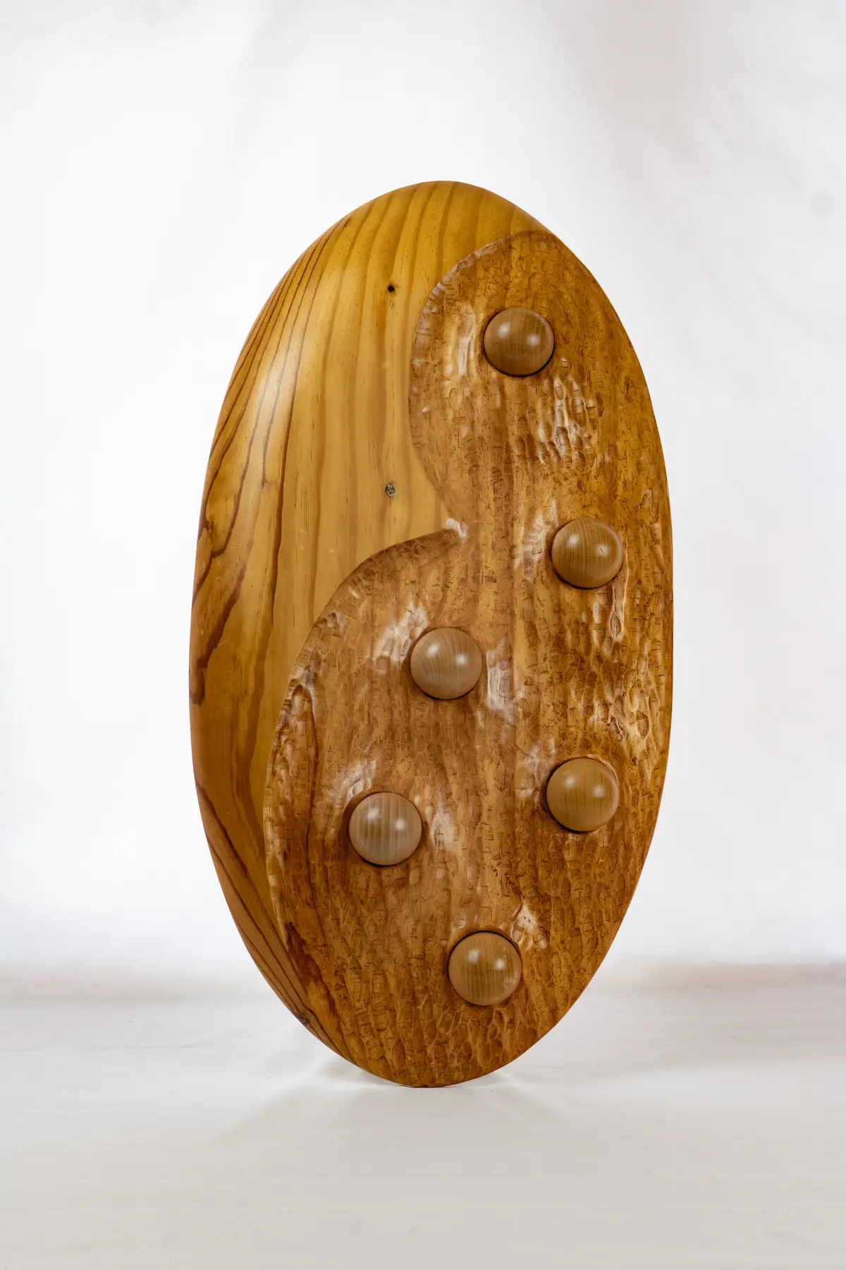 Panel ovalado de pino con varias esferas de madera embutidas en su superficie