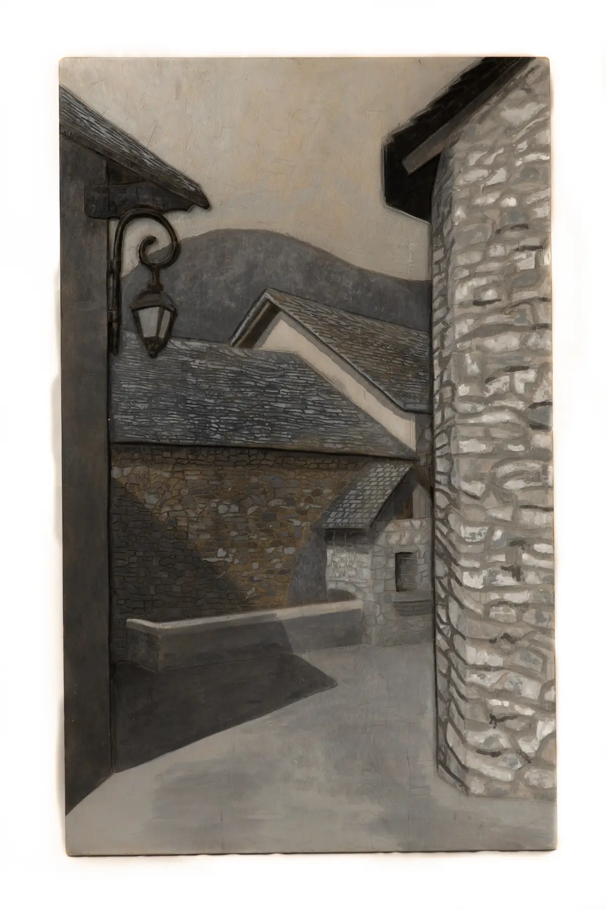 Relieve de haya policromado en gris que representa una calle empedrada entre dos casas de piedra, con un farol de forja y tejados al fondo