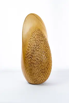 Ver Semilla de vida de frente, con la cara tallada en escamas ocupando el cuerpo de la pieza a tamaño completo